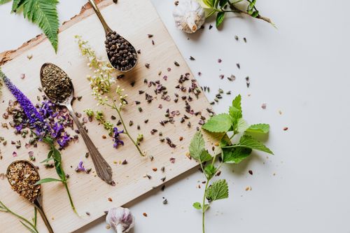 Free Overhead shot of herbs and spices on a wooden chopping board with spoons, showcasing culinary ingredients. Stock Photo