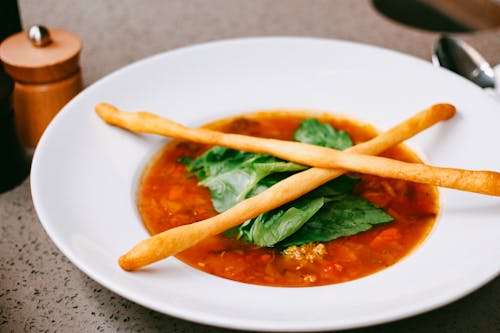 Free Close-Up Photograph of a Tomato Soup with Green Leaves Stock Photo