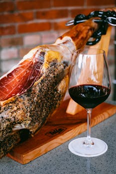 Artisan cured ham with a glass of red wine in a cozy rustic ambiance.