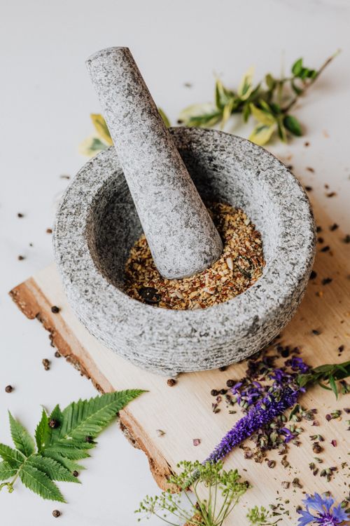 Free Granite mortar with pestle grinding mixed herbs and spices on a rustic wooden board. Stock Photo