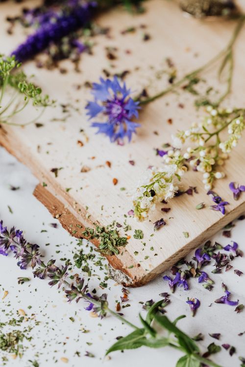 Free A close-up of fresh herbs and flowers on a rustic wooden board, perfect for culinary or herbal themes. Stock Photo