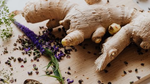 Close-up of fresh ginger and various spices laid out on a chopping board for culinary use.