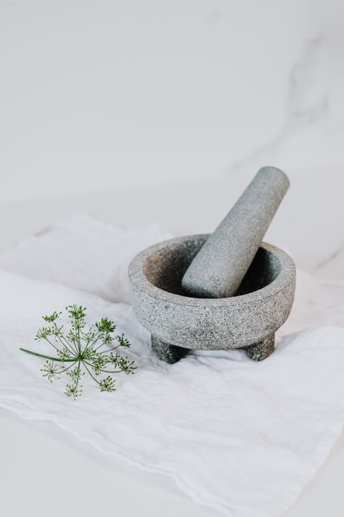 Free Minimalistic image of granite mortar and pestle resting on a white fabric with greenery accent. Stock Photo