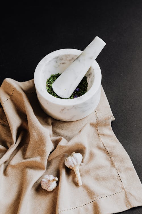 Close-Up Shot of Mortar and Pestle Near Garlics