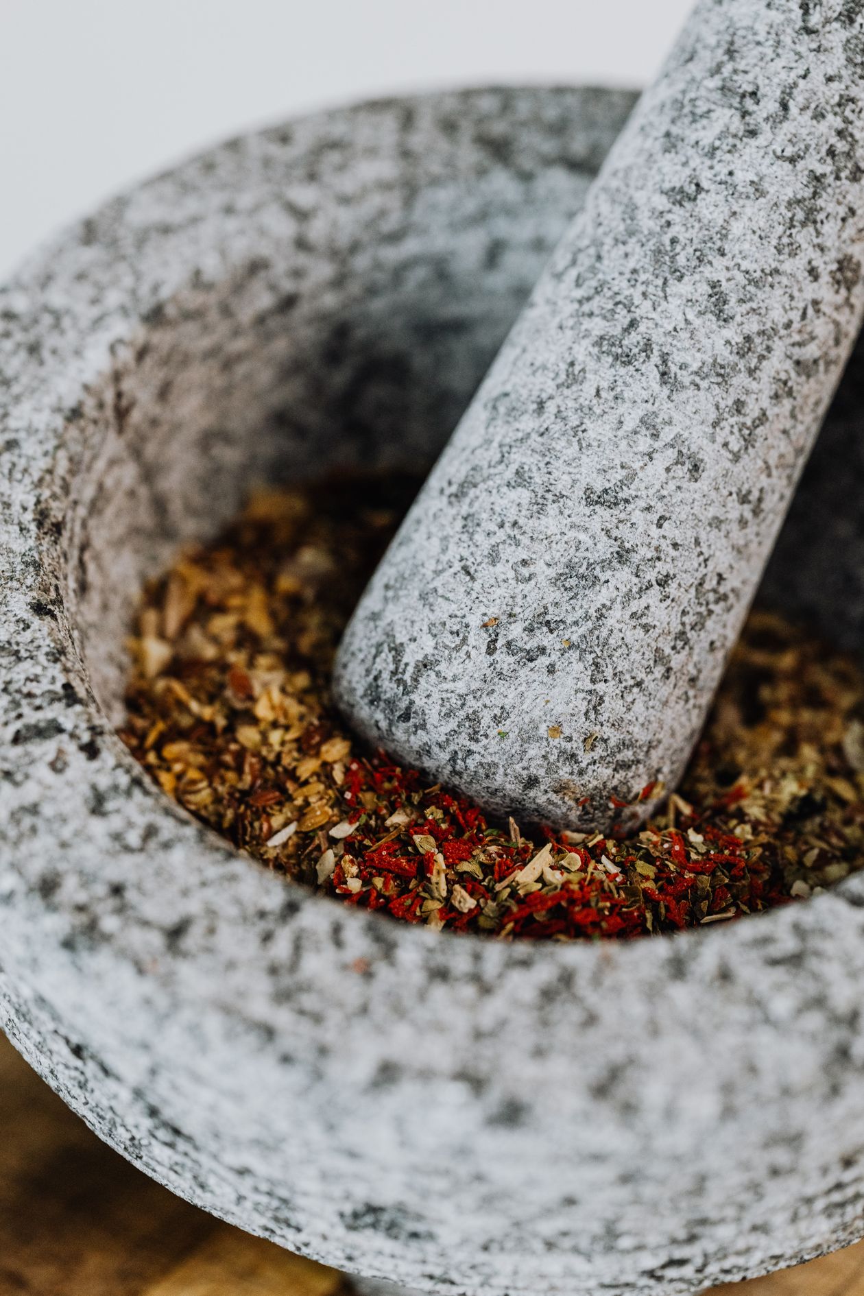 Jerk chicken seasoning spices being ground in a granite mortar and pestle