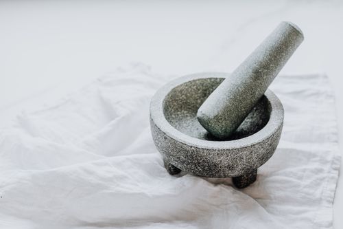 Free A stone mortar and pestle placed on a white textile background in a minimalist style. Stock Photo