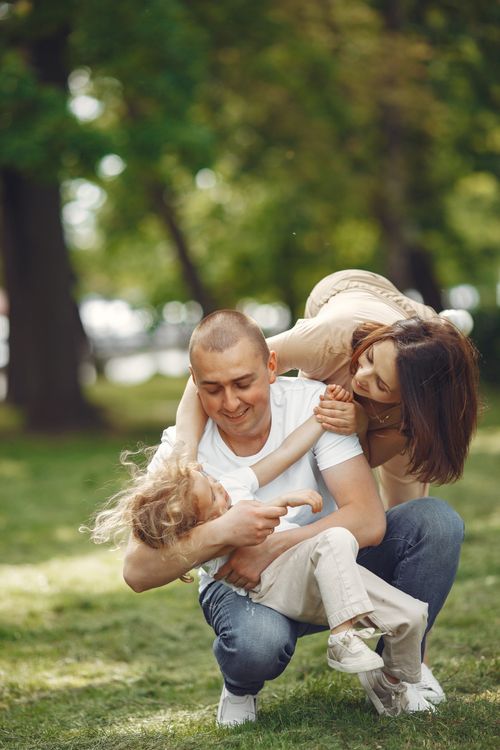 Free A joyful family playing together in a sunny park, embracing love and connection. Stock Photo