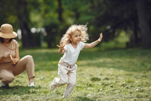 Free Photo of a Cute Kid in a White Shirt Running on the Grass Stock Photo