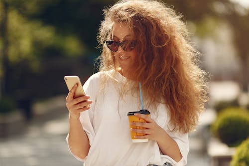 A Woman in White Crew Neck T-shirt Holding a Smartphone