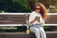 A Woman in Blue Denim Jeans Sitting on Brown Wooden Bench