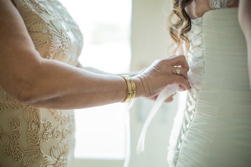 Free Crop faceless mother lacing up classy wedding dress on daughter Stock Photo