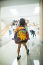 Unrecognizable child with backpack walking in crowded hall