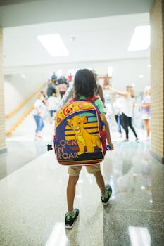 A child with a colorful backpack walks through a busy school hallway.