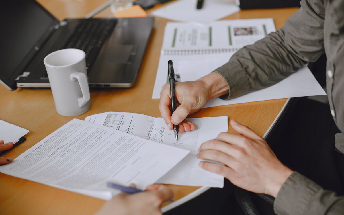 Close-up of hands signing a document at a table during a tenancy agreement meeting