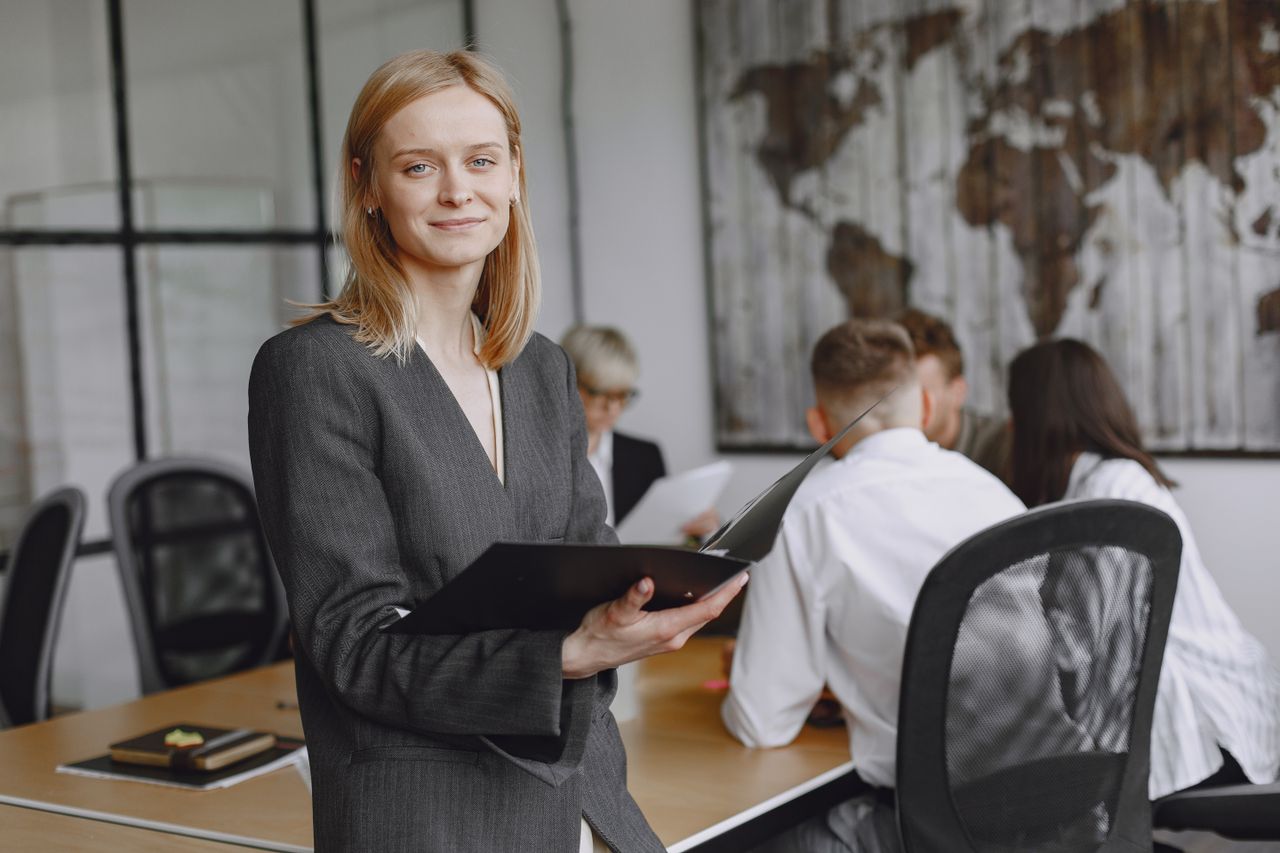 Businesswoman in a gray suit holding a folder during a meeting