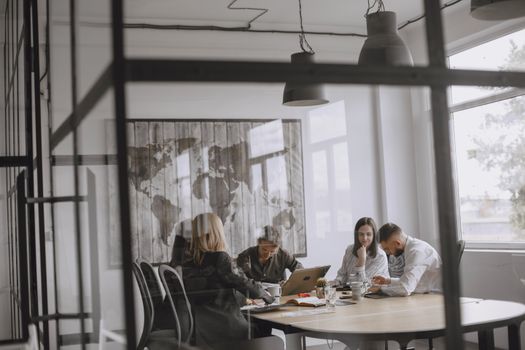 A group of professionals collaborate in a modern office with a world map decoration.