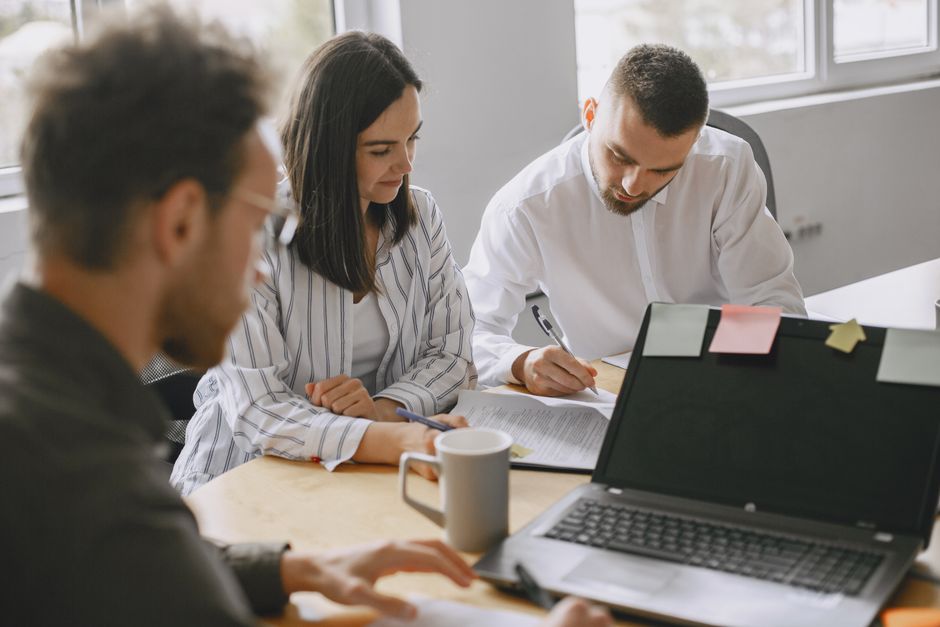 Equipo enfocado discutiendo trabajo en un ambiente de oficina moderno y luminoso.