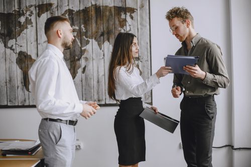 Free Three young professionals discussing documents in a modern office space. Stock Photo