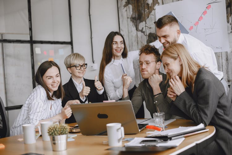 Group Gathering Around Laptop During Business Meeting