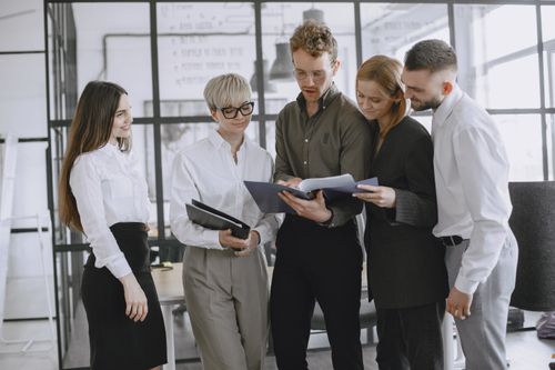 Free A diverse group of professionals collaborating and discussing documents in a modern office space. Stock Photo