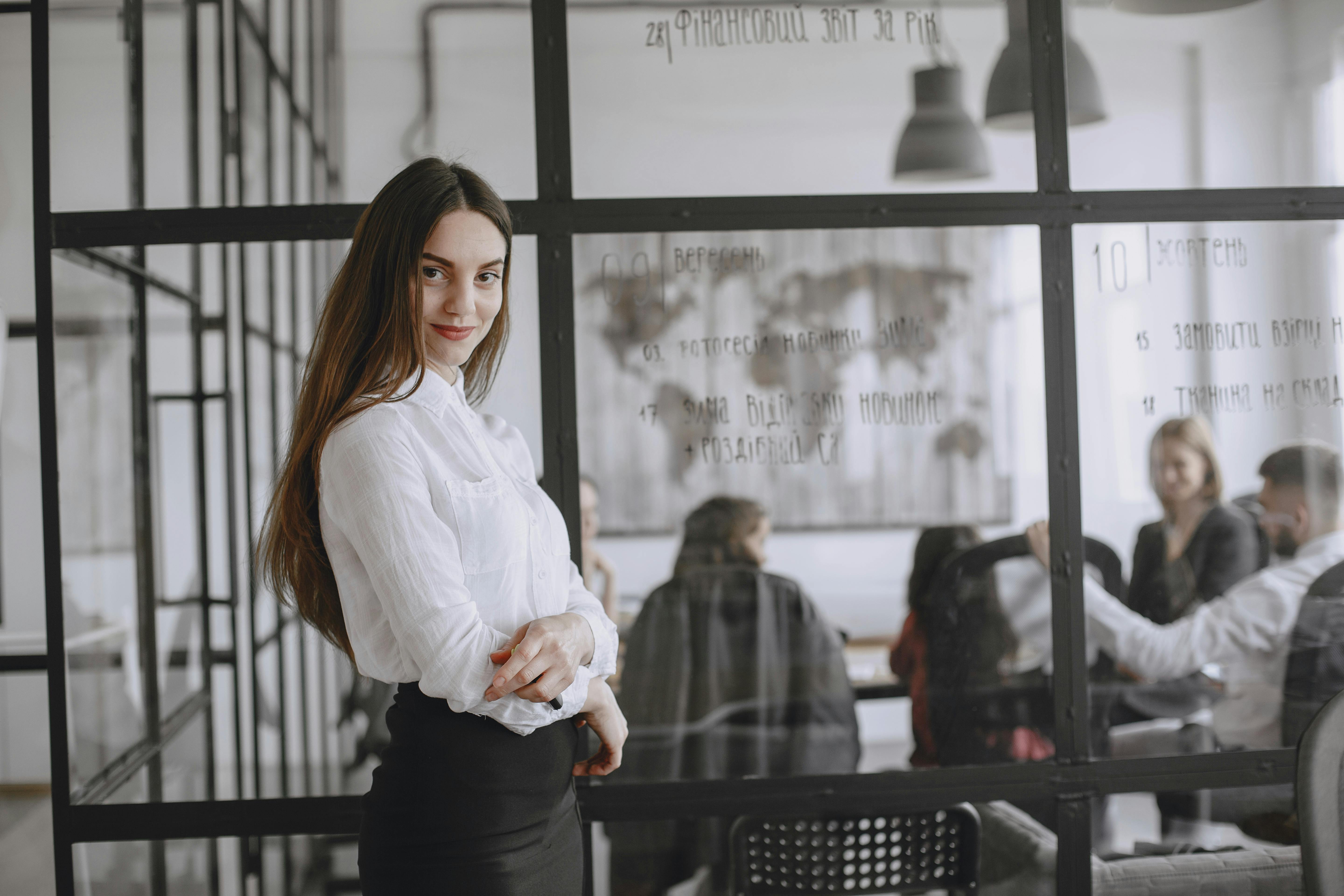 职业女性自信地站在现代化的办公室里，与背景是会议室的同事在一起