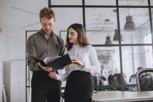 Free Two professionals discuss documents in a modern office environment. Stock Photo