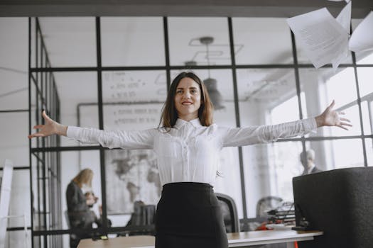 Smiling woman with arms open wide in a modern office environment.