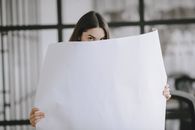 Woman Hiding Behind a Big Sheet of Paper