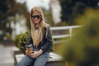 Girl Sitting on Bench with Drink in Disposable Cup 