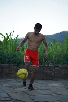 Shirtless young man practicing soccer with a yellow ball outdoors. Fitness and sport concept.