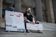 Anonymous protesters with BLM placards on stairs in city