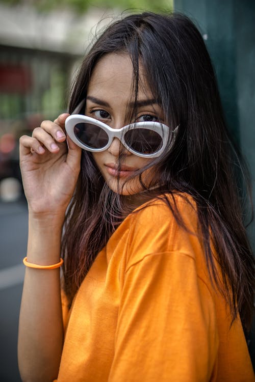 Woman in Orange Crew Neck T-shirt Wearing White Framed Sunglasses