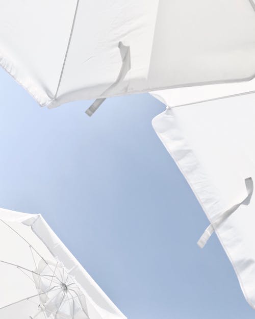 Low Angle Shot of White Umbrellas Under Blue Sky
