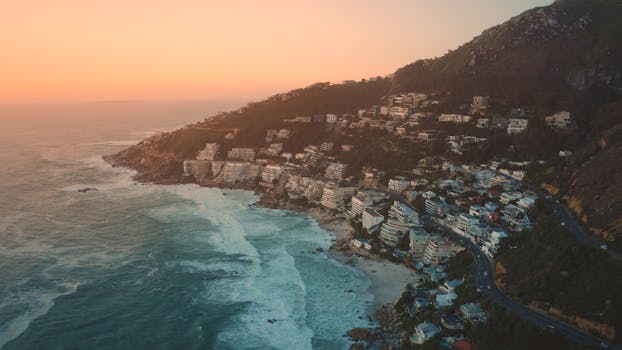 Breathtaking aerial view of Cape Town's coastline during dusk, showcasing stunning ocean and cityscape.