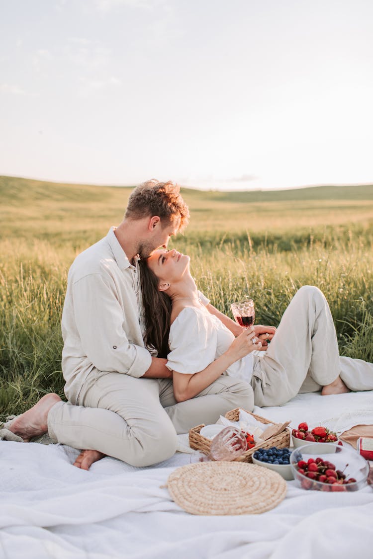 Man And Woman Sitting On Grass Field