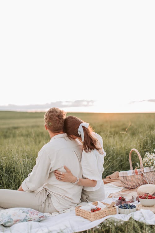 Back View Shot of a Couple Sitting on a Picnic Blanket while Looking at the Beautiful Sky