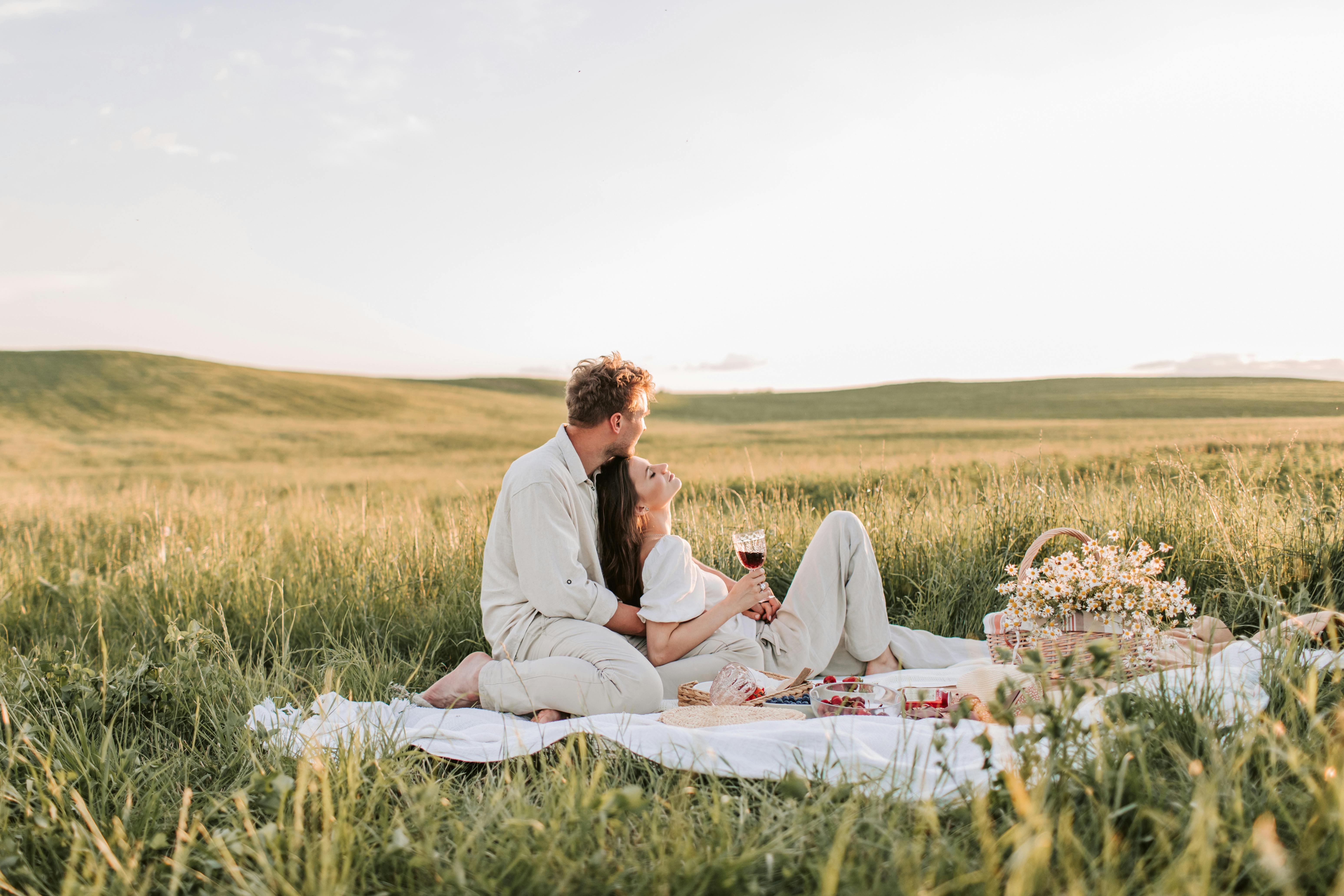 man and woman sitting on grass field