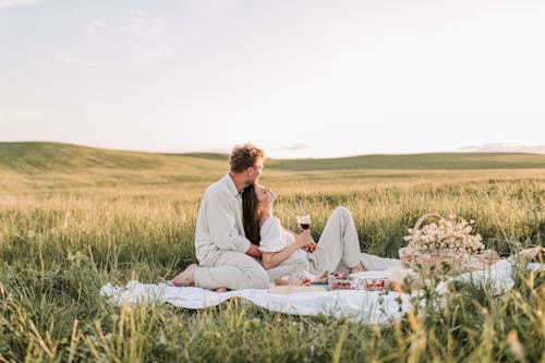 Man And Woman Sitting On Grass Field