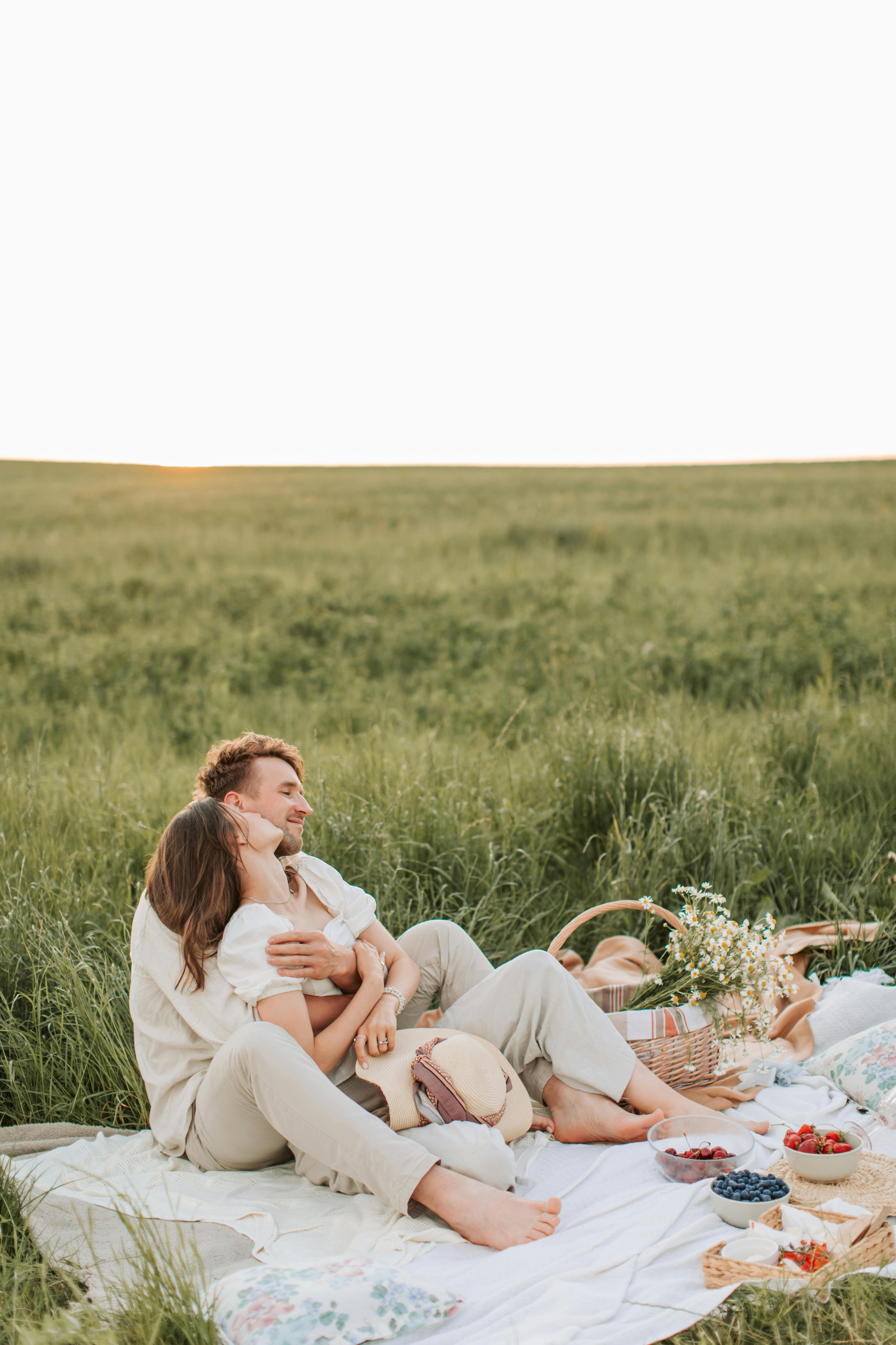一对恩爱的夫妇在绿草如茵的草地上野餐，四周环绕着大自然的美景
