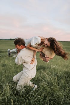 日落时分，一对夫妇在风景优美的草地上尽情玩耍，充满了爱与欢乐