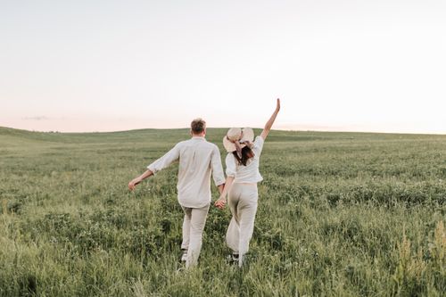 Free A couple enjoying a romantic walk in a sunlit field, holding hands in nature. Stock Photo