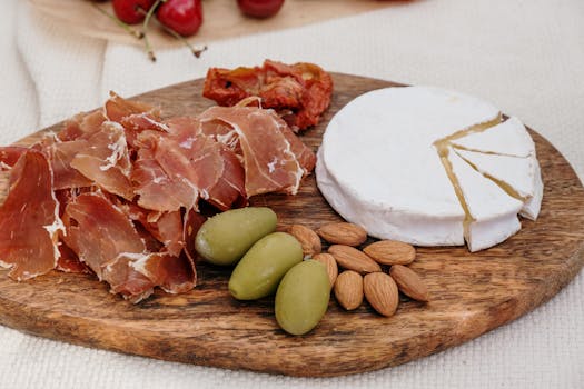 A delectable charcuterie board featuring brie cheese, prosciutto, olives, and almonds.