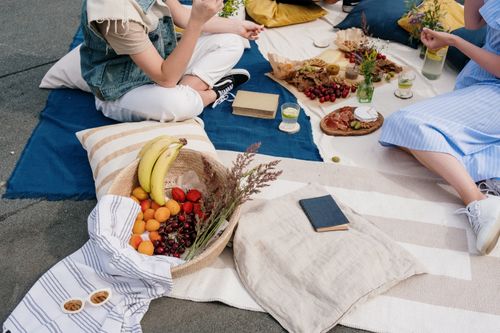 Free A vibrant outdoor picnic scene with fresh fruits, snacks, and friends enjoying a sunny day. Stock Photo