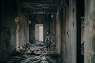 在光线昏暗、堆满碎片的废弃建筑走廊里，站着一个人