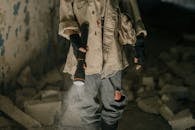 Person in Brown Jacket and Blue Denim Jeans Holding Black Rifle