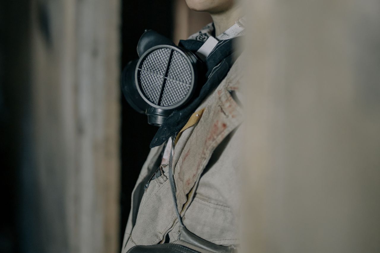 a person wearing a respirator in a dimly lit urban environment conveyi