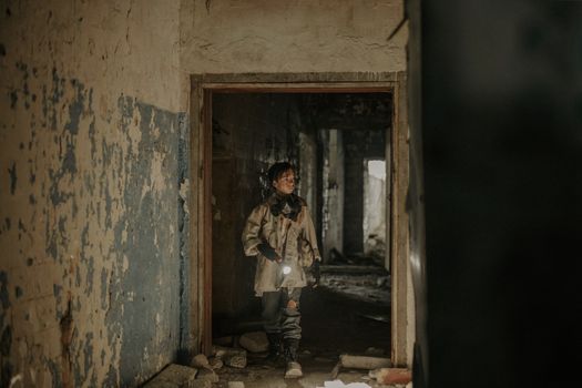 A young man exploring an abandoned building with a flashlight, showcasing urban decay and survival themes.