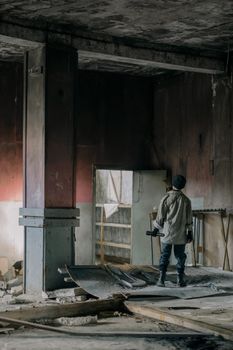一名年轻人独自站在一栋摇摇欲坠的废弃建筑里，探索着城市的衰败
