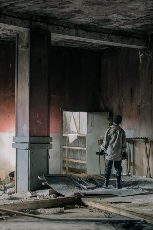 Free A young man stands alone in a crumbling, abandoned building exploring urban decay. Stock Photo