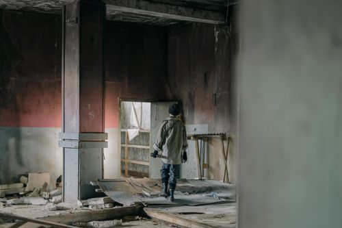 Free A person exploring an abandoned building, evocative of a post-apocalyptic setting, highlighting decay. Stock Photo